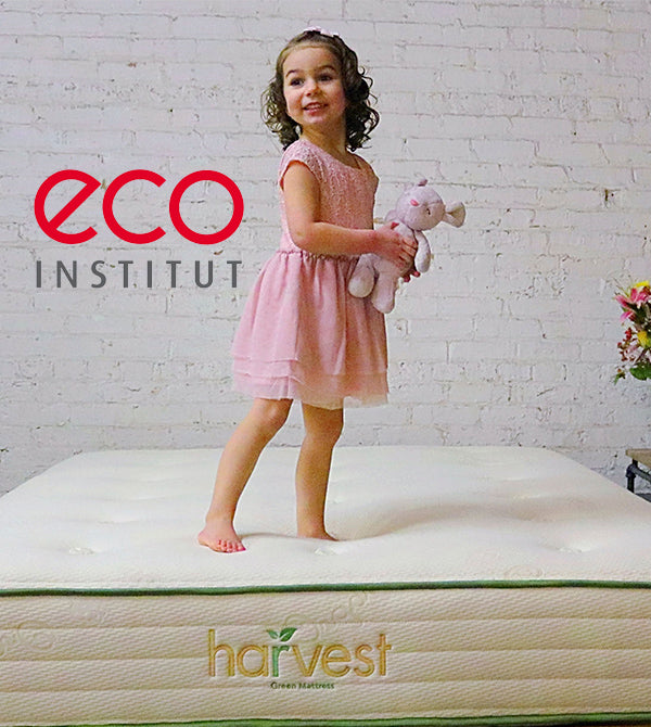 eco-INSTITUT Certification logo overlaid on an image of a little girl standing on our harvest green original mattress 