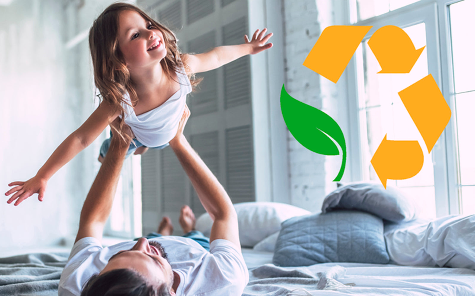 Father playing with his daughter on top of our mattress with our environmentally safe logo 