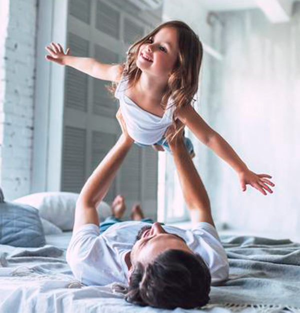 Young father and daughter playing on our mattress that does not contain any synthetic memory foams