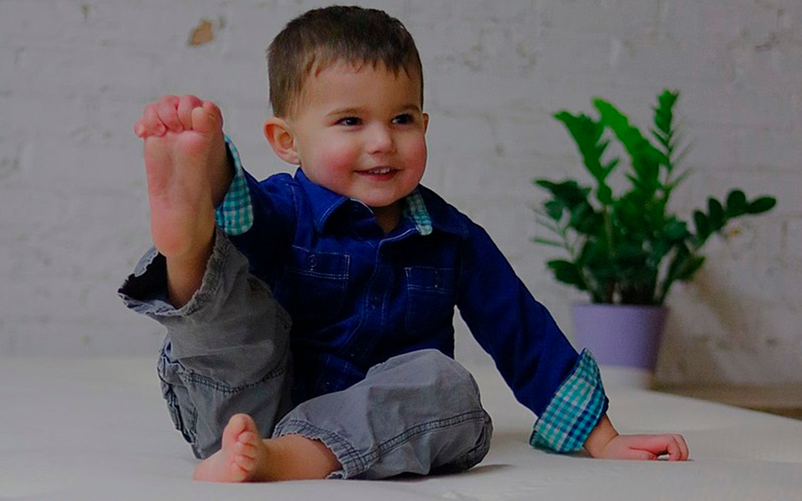 one of our harvest kid models showing the bottom of his foot laying on our harvest green original mattress